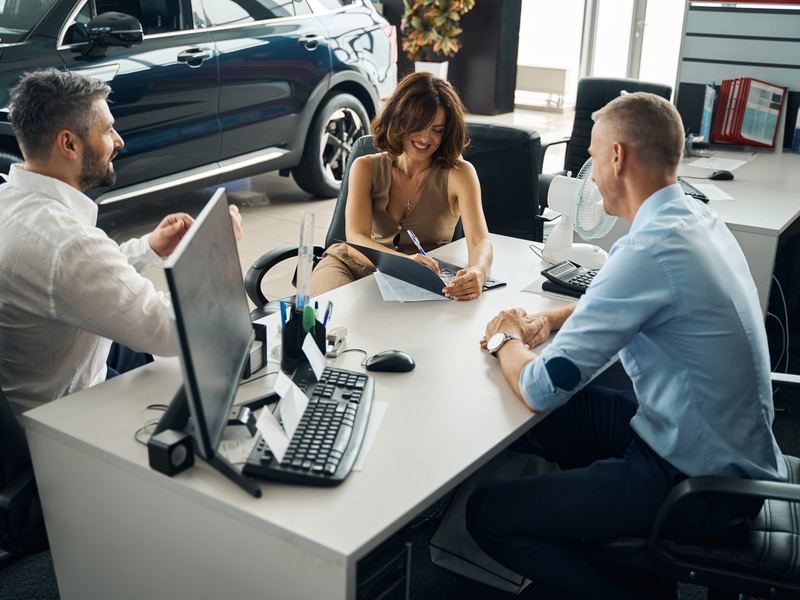 Happy couple financing a car at the dealership